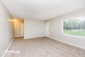 Indianapolis house for rent - A room with a carpeted floor and a window showing a green lawn outside.