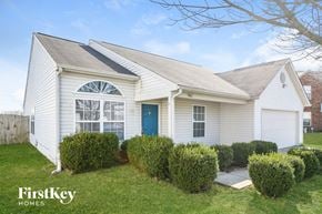 Indianapolis house for rent - A white house with a blue door and a window with a sun design on it.