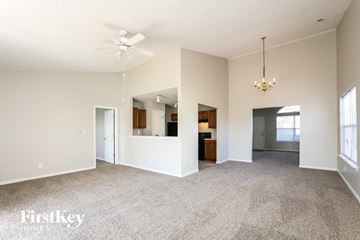 Indianapolis house for rent - A spacious living room with a grey carpet and a chandelier hanging from the ceiling.