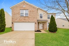 Indianapolis house for rent - A brick house with a garage door and a tree in front.