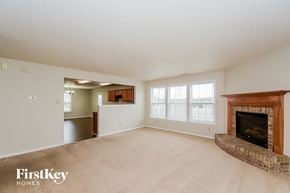 Indianapolis house for rent - A spacious living room with a fireplace and a view of a hallway and kitchen.