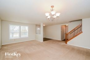 Indianapolis house for rent - A spacious room with a chandelier and a staircase.