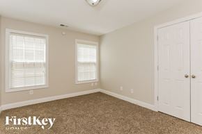 Atlanta house for rent - a bedroom with a carpeted floor and two windows and a white door