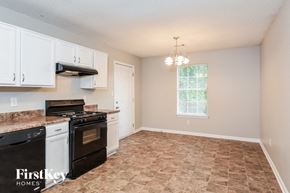 Atlanta house for rent - a kitchen with white cabinets and black appliances and a window
