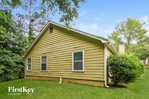 Atlanta house for rent - a yellow house with a green lawn and trees