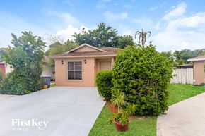 Boynton Beach house for rent - a small house with a driveway and a yard with plants and trees