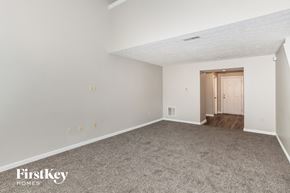 Loveland house for rent - A spacious empty room with a carpeted floor and a door on the right side.