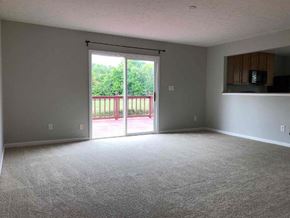 Indianapolis house for rent - A room with a grey carpet and a sliding glass door leading to a backyard.