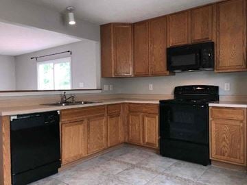 Indianapolis house for rent - A kitchen with wooden cabinets and black appliances.