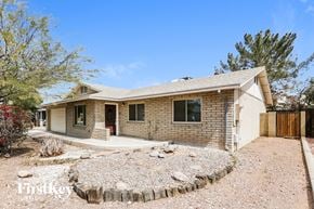 Tempe house for rent - a small tan brick house with a gravel yard and a wood fence