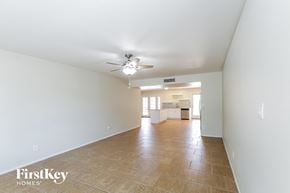 Tempe house for rent - a spacious living room with white walls and a ceiling fan