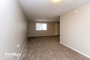 Indianapolis house for rent - A carpeted room with a window and a door in the background.