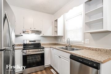 Charlotte house for rent - a kitchen with white cabinets and granite counter tops and stainless steel appliances