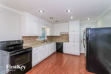 Acworth house for rent - A kitchen with white cabinets and a black refrigerator.
