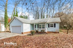 Charlotte house for rent - A house with a garage and a front porch is surrounded by trees and has fallen leaves on the ground.