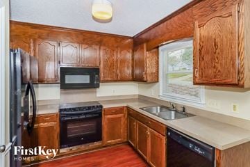 Charlotte house for rent - A kitchen with wooden cabinets and a black dishwasher.