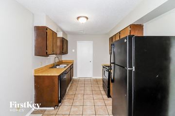 Memphis house for rent - a kitchen with black appliances and wooden cabinets and a black refrigerator