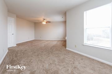 Indianapolis house for rent - a spacious living room with carpet and a ceiling fan