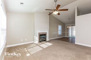Greensboro house for rent - an empty living room with a fireplace and a ceiling fan