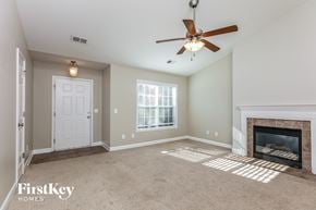 Greensboro house for rent - a living room with a fireplace and a ceiling fan