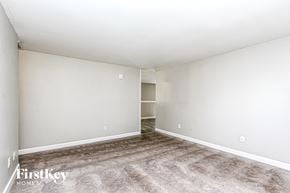 Indianapolis house for rent - A spacious room with a carpeted floor and a door on the left side.