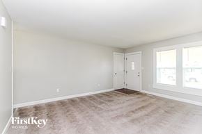 Indianapolis house for rent - A spacious room with a carpeted floor and a door leading to another room.