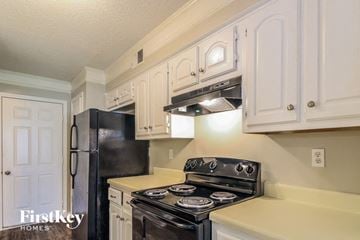 Memphis house for rent - a kitchen with white cabinets and black appliances