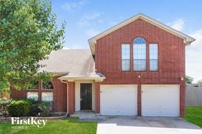 Arlington house for rent - A red brick house with a black door and two white garage doors.