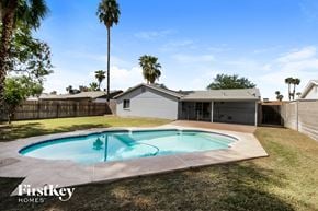 Tempe house for rent - a backyard with a pool and a house with palm trees