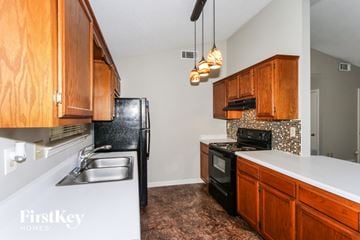 Millington house for rent - A kitchen with wooden cabinets and a black fridge.