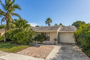 Lake Worth house for rent - a white house with palm trees and a driveway