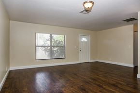 Lake Worth house for rent - an empty living room with wood floors and a window