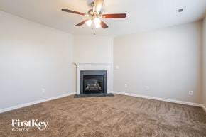 Greensboro house for rent - A living room with a fireplace and a ceiling fan.
