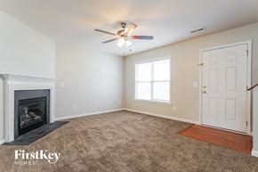 Greensboro house for rent - A spacious room with a fireplace and a ceiling fan.