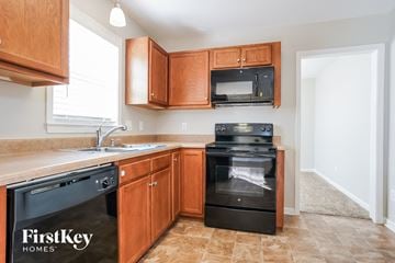 Greensboro house for rent - A kitchen with wooden cabinets and black appliances.