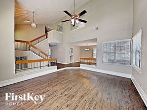 Garland house for rent - A spacious room with a wooden floor and a staircase with a metal railing.