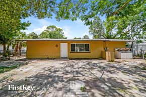 Bradenton house for rent - A yellow house with a white door and windows is surrounded by trees.