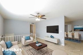 Phoenix house for rent - A living room with a white couch, a coffee table, and a flat screen TV mounted on the wall.