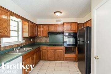 Memphis house for rent - a kitchen with wooden cabinets and a black refrigerator and a sink