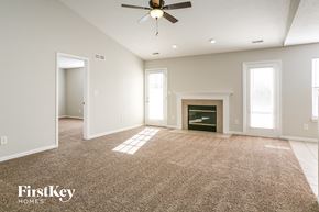 Indianapolis house for rent - A spacious room with a fireplace and a carpeted floor.