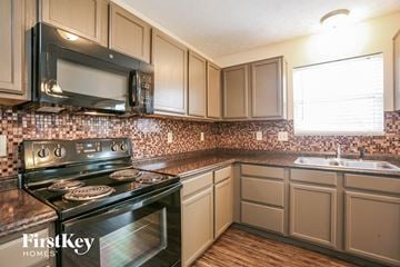 Indianapolis house for rent - A kitchen with a black stove and a black microwave above it.