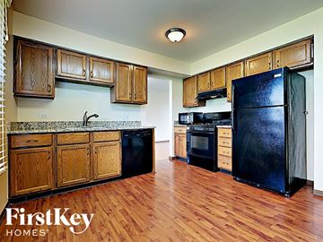 Matteson house for rent - a kitchen with wood floors and black appliances