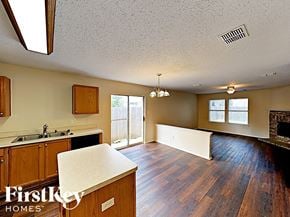 Fort Worth house for rent - an empty kitchen and living room with a fireplace and wood floors