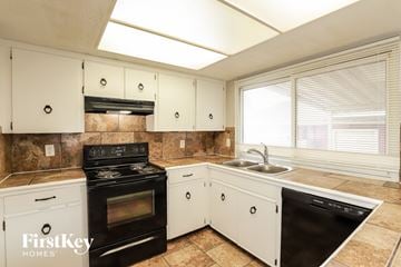 Grandview house for rent - A kitchen with a black stove top oven, white cabinets, and a black dishwasher.