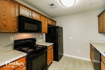 Covington house for rent - A kitchen with black appliances and wooden cabinets.