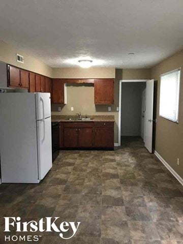 Indianapolis house for rent - A kitchen with a white fridge and brown cabinets.