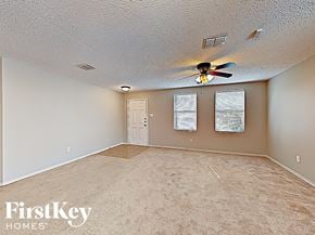 Denton house for rent - an empty living room with a ceiling fan and a door