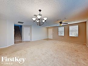 Denton house for rent - an empty living room with a ceiling fan and a chandelier