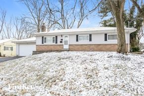 Hazelwood house for rent - A house with a white garage door and a brown tree in front.