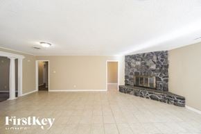 Bartlett house for rent - a living room with a stone fireplace and a tiled floor